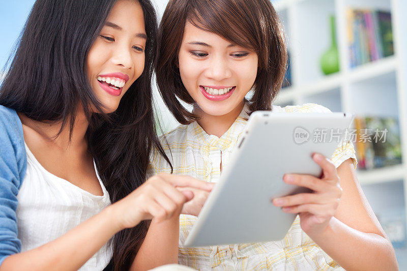 Two Beautiful Young Women Having Fun With Digital Tablet重复图片